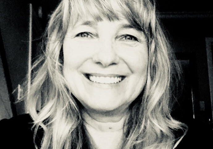 Black and white portrait of a smiling woman with wavy hair.